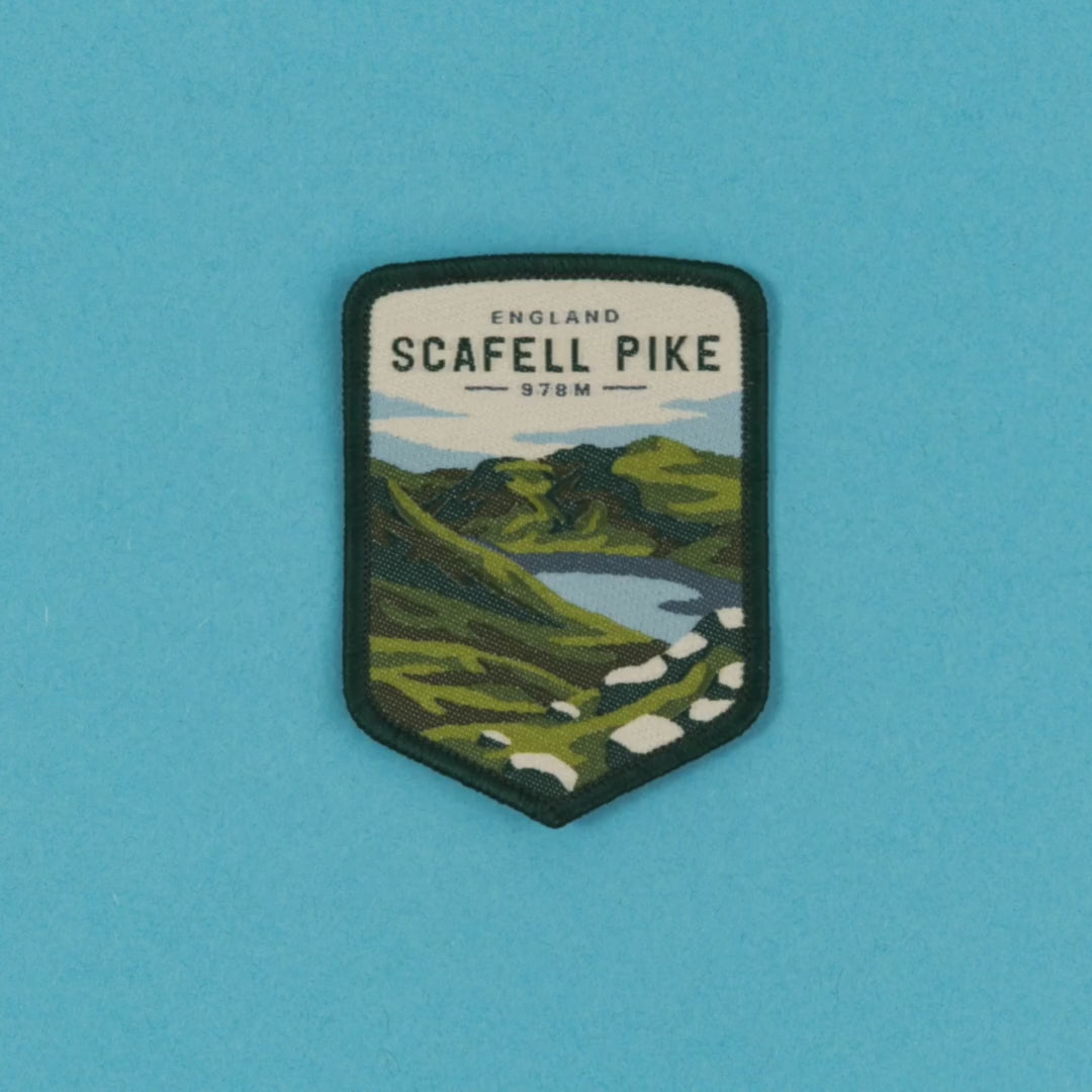 video depicting the Scafell Pike patch on a backing card, jumping onto a bag and then being applied to the bag using an iron