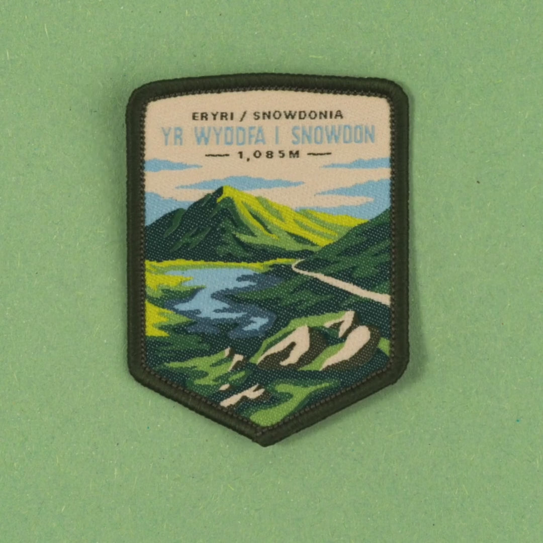video depicting the Snowdon patch on a backing card, jumping onto a bag and being applied via the easy iron on backing